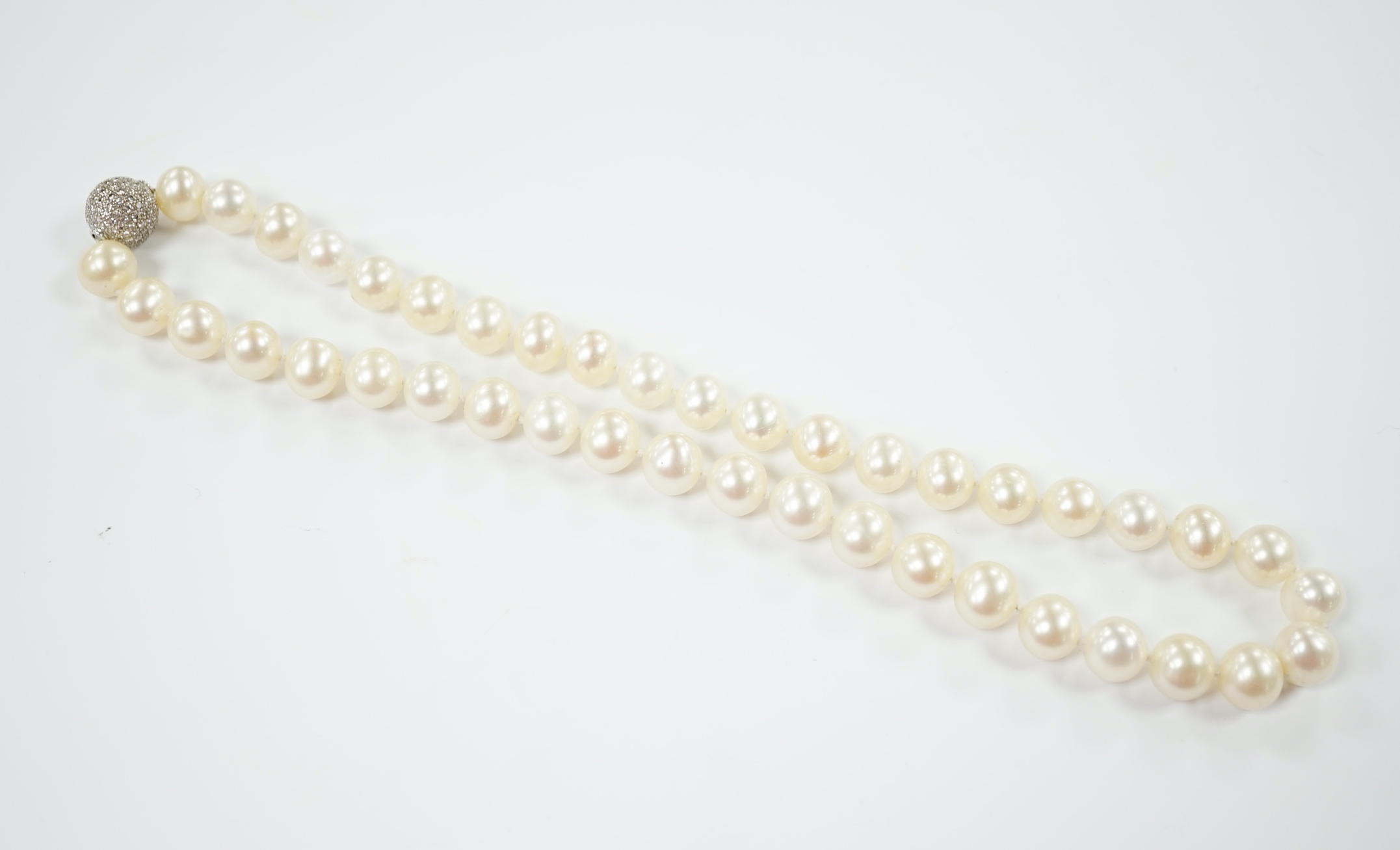 A modern single strand cultured pearl necklace with pave set diamond mounted spherical yellow metal clasp, 44cm.